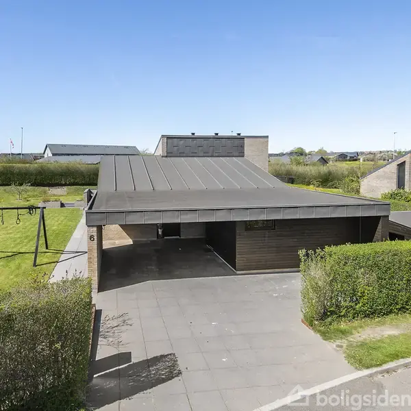 En moderne carport foran et hus danner skygge, mens en legeplads med gyngestativer ses til venstre. Omkringliggende hække og himmel skaber en rolig bolignabo-kontekst.