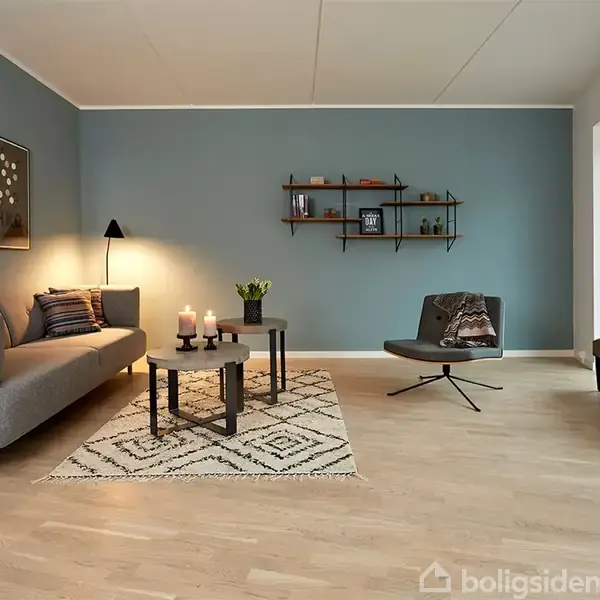 Sofa med puder står ved en væg, hvor hylder og billeder med teksten "C6H6" hænger. En lænestol er placeret ved vinduer. Stearinlys og planter på sofabordet på gulvtæppe.