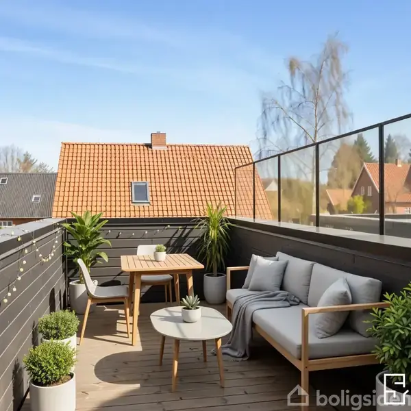 En altan med sofa og bord omgivet af planter. Altanen har sort rækværk og udsigt til huse med rødt tag. Sollys og klar himmel giver en behagelig atmosfære.