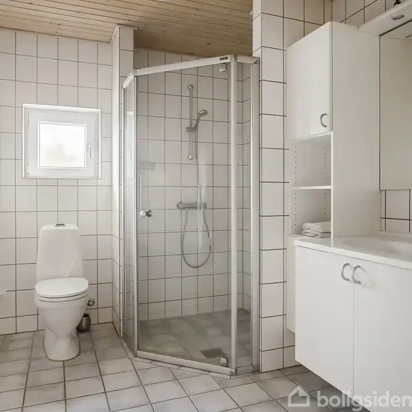 Et lyst badeværelse med hvidt flisegulv og vægge. En brusekabine står ved siden af et toilet. Vaskemaskine og skabsplads supplerer den funktionelle indretning.
