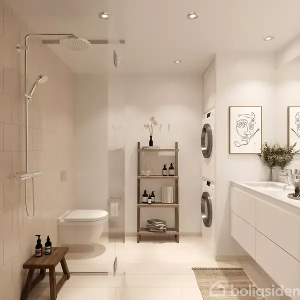 En moderne badeværelsesindretning viser en væghængt toilet og bruser til venstre, en hylde med toiletartikler i midten og vaskemaskine med tørretumbler til højre. En plante pynter ved vasken. To minimalistiske kunsttryk hænger på væggen.