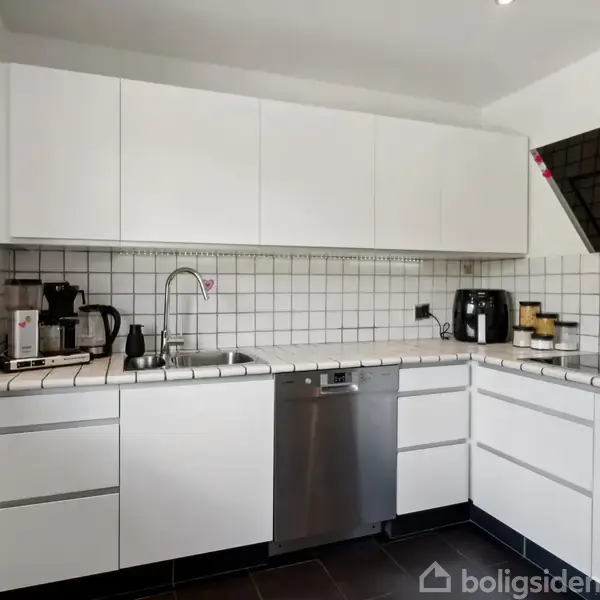 Hvidt køkken med fliser; kaffemaskine og brødrister på bordet; opvaskemaskine under. V-formet emhætte over kogeplader. Kalender og ur på væggen. Sort gulv skaber kontrast.