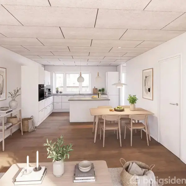 Et lyst køkkenalrum med et spisebord til fire, planter og vægkunst. Køkkenet i baggrunden har en ø, hvide skabe og store vinduer, der slipper lys ind.