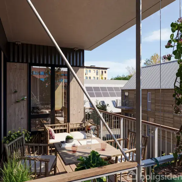 En terrasse med træmøbler og planter, arrangeret omkring et bord, skaber en hyggelig atmosfære. Omgivet af moderne bygninger og solpaneler på taget, er der klar himmel i baggrunden.