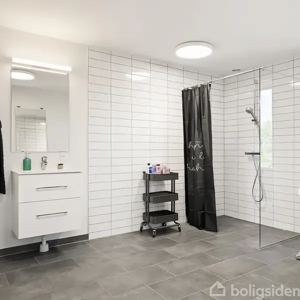 Et moderne badeværelse med hvidt flisegulv med en brusekabine med sort forhæng. Til venstre er der et toilet og en håndvask med underskab. En fritstående badekar er i højre side.