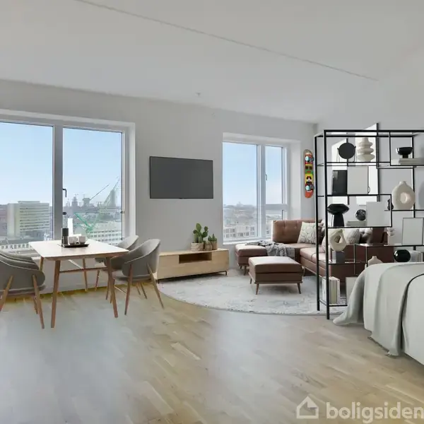 Et lyst og moderne rum med store vinduer viser en spisestue med bord og stole til venstre, en stue med sofa og reol til højre, og en seng i forgrunden.