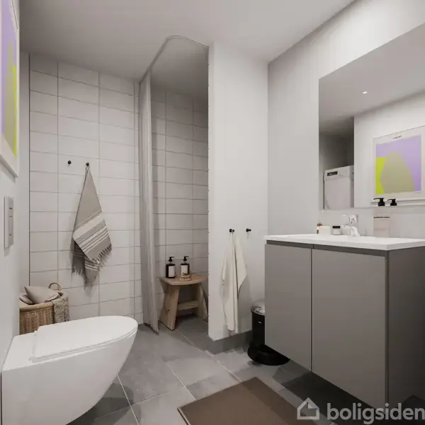 Et moderne badeværelse med et hvidt toilet til venstre, en vask med spejl til højre, og en brusekabine med flisevæg i baggrunden. Håndklæder hænger på kroge.