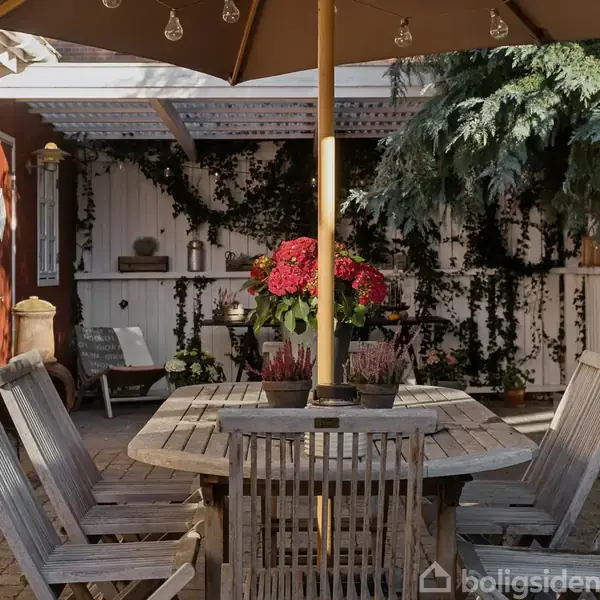Træbord omgivet af seks stole står under en parasol på en terrasse. Blomster er placeret på bordet, mens murstensvægge og klatreplanter udgør baggrunden.