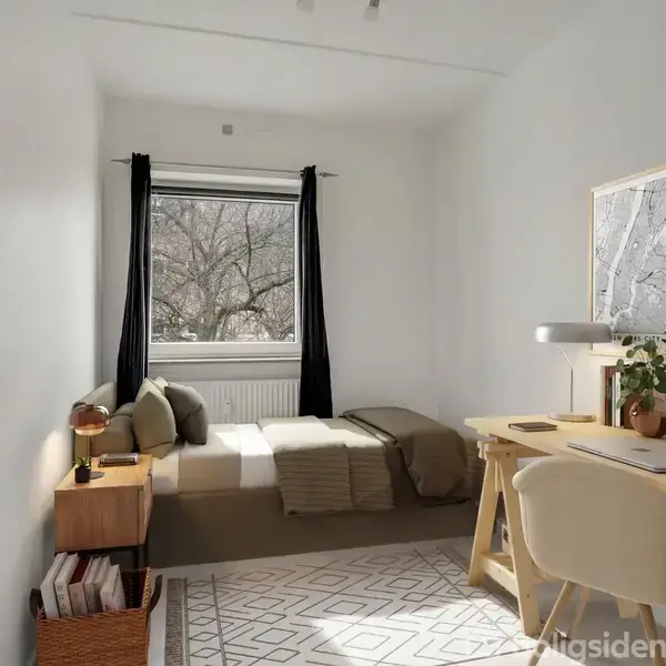 Et værelse med en seng til venstre ved siden af et vindue med trækroner udenfor. Et skrivebord til højre har en lampe og bøger. Væggene er hvide.