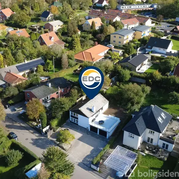 EDC pin marker viser et specifikt hus i en grøn forstad, omgivet af flere boliger med haver og træer, under en blå himmel. Tekst: "boligsiden".