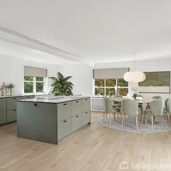 En moderne køkken-alrum viser et centralt grønligt køkkenø-bord med skuffer, omgivet af skabe. Ved siden af er en spisestue med bord og seks stole på et gråt tæppe. Lyse vægge, store vinduer, planter og en pendellampe skaber en lys og åben atmosfære.