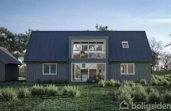 Et moderne hus står i en grøn have. Husets facade har store vinduer og en mørk tag. Omgivet af buske og græs, med træer i baggrunden.