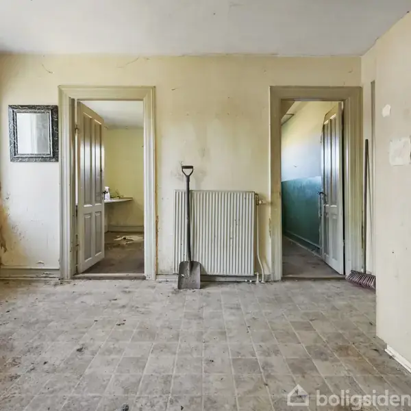 Slidt køkken med skovl stående ved radiator, åbninger til to tilstødende rum; sollys strømmer ind fra et vindue til venstre, rengøringsudstyr ses i baggrunden.