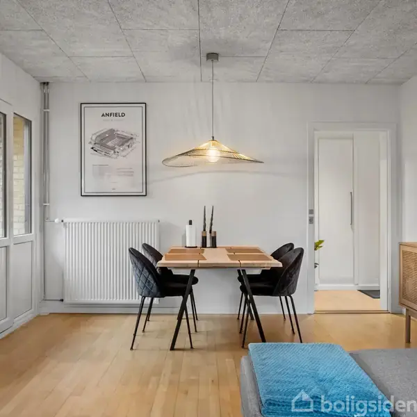 Et moderne køkken med hvide skabe og rustfri apparater. Der er en indbygget ovn, skærpet knive og mikrobølgeovn på bordpladen. Et vindue viser en bygning og træer udenfor.