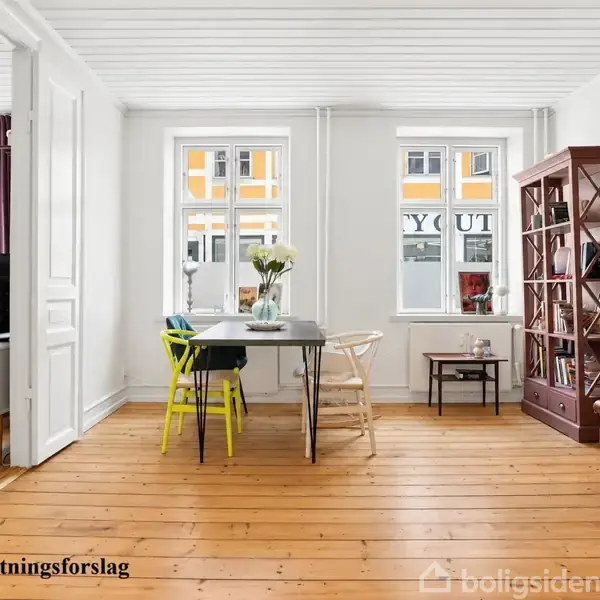 Stue med spisebord og varierede stole står foran to vinduer. Til højre er en brun reol og et stort spejl. Tekst: "Indretningsforslag".