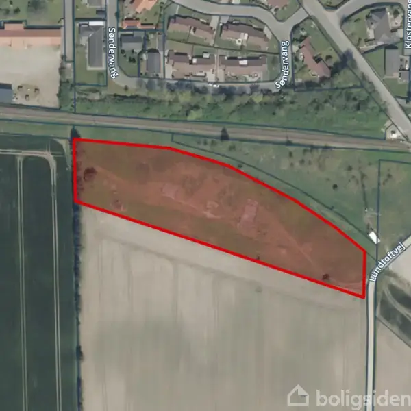 Et luftfoto viser et markområde omgivet af marker og beboelse. Et rødt omrids markerer et trekantet jordstykke. Vejnavne som Klokkestøbervej og Ulvetandvej er synlige.
