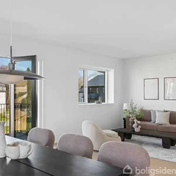 Stue med brun sofa og sofabord, placeret ved siden af et stort vindue, der giver udsigt til have. Spisebord med stole og en moderne lampe hænger over bordet.