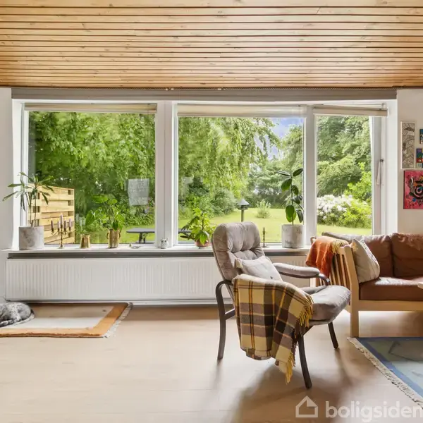En stue med en hund, der ligger på et tæppe. Der er en stol med tæpper og en sofa. Store vinduer viser en grøn have udenfor.