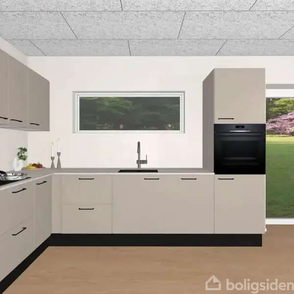 Et moderne køkken har beige skabe og sorte greb. Indbygget i en hvid væg med et smalt, rektangulært vindue. En åben dør fører til en grøn have.