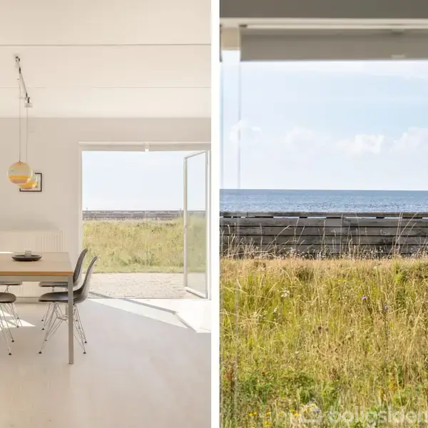 Spisebord med stole i en lys stue, hvor døre står åbne mod en kystlinje. Udsigt til græs og hav, der giver en frisk og naturlig atmosfære.
