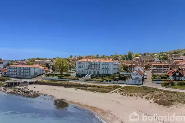 Et bordfodboldspil står klar til brug i et lyst rum med et bordtennisbord i baggrunden og stole samt et bord ved et vindue.