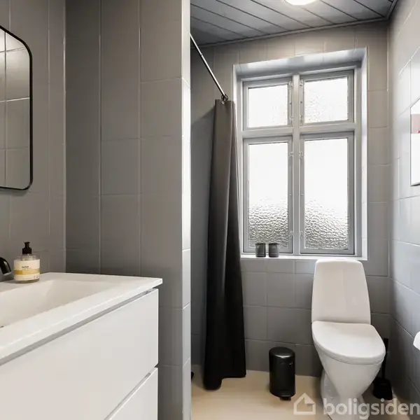 Et moderne badeværelse med en hvid vask og sort armatur til venstre, et bruseområde med sort forhæng til højre, og et toilet ved et vindue. Grå vægge og loft.