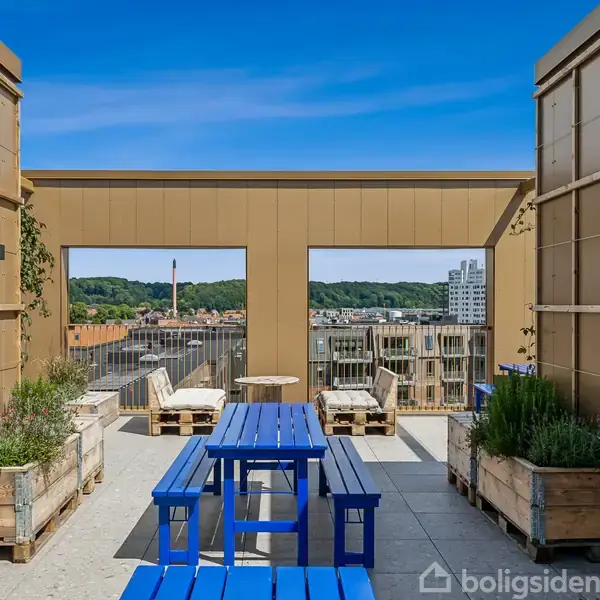 Blåt havebord og bænke står på en tagterrasse omgivet af plantekasser. I baggrunden ses byens skyline og grønne områder under en klar blå himmel.