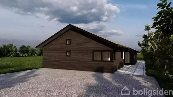 En træbeklædt bygning står stille på en grusbelagt indkørsel omgivet af grønne træer og græs. Himlen er delvist overskyet.