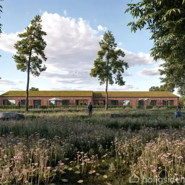 En lang, lav bygning med græs på taget står i en frodig mark. To personer går gennem det høje græs blandt vilde blomster og træer under en blå, skyet himmel.