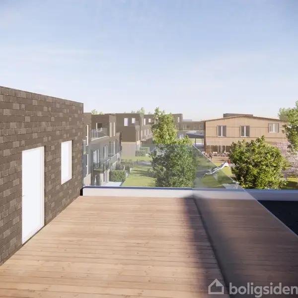 Bygning med murstensfacade og glasværn står på en balkon, omgivet af grønne træer og andre moderne huse i en forstad.