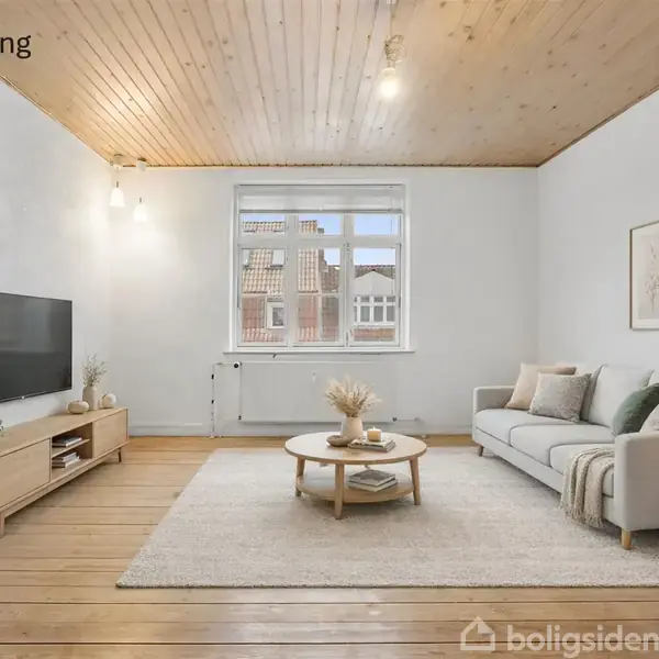 Stue med sofa, sofabord og TV. Sofaen står på et tæppe ved siden af et lille bord med lampe. TV'et er på en skænk. Trævægge og loft. Vindue.
Tekst: "Visualisering".