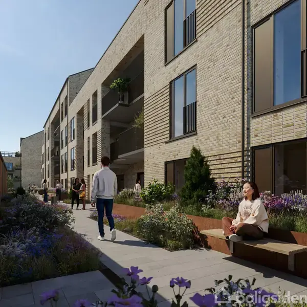 En kvinde sidder på en bænk i en moderne boligområde med grønne planter og blomsterbede, mens flere mennesker går langs en sti mellem murstensbygninger.