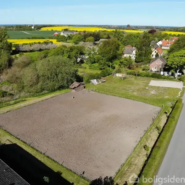 Ridebane i brug i landligt område med små huse og veje. Gyldne marker og træer omgiver pladsen, bidrager til en fredfyldt og åben atmosfære.