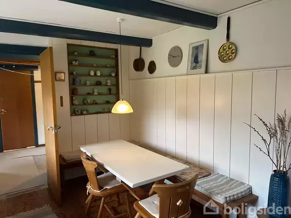 Håndvask med dispenser ved siden af, står i et flisebelagt badeværelse. Bruser med flerfarvet forhæng i baggrunden. Funktionelt design i lille rum.