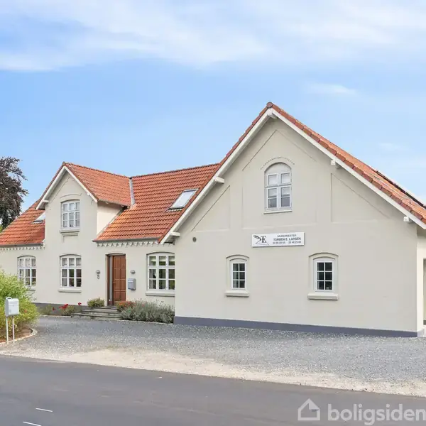 Et hvidt hus med rødt tegltag står ved en vej. Et skilt på huset siger: "Svinninge Begravelsesforretning, Benedikte Algot". Der er grusparkering og buske omkring.