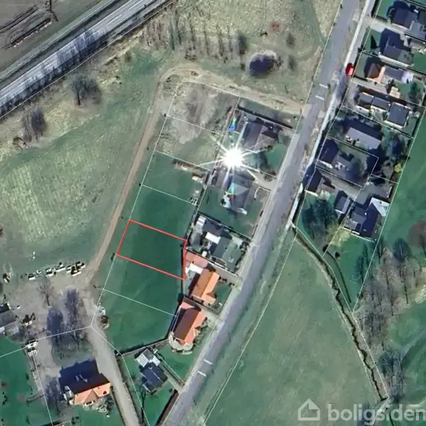 Grønt landområde afgrænset af røde linjer ligger midt i et boligområde med nærliggende huse og veje.