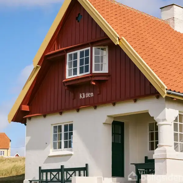 Bygning med rødt træværk og skråt tag, har et skilt med teksten "Klitten" over et vindue. Omgivelserne fremstår som et solrigt boligområde.