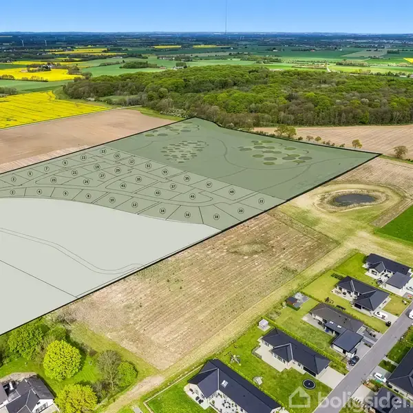 Luftfoto viser en opdelt mark i et landligt område med opdyrkede marker omkring. Der er en klar optegning af byggegrunde ved siden af en eksisterende boligudvikling med huse.