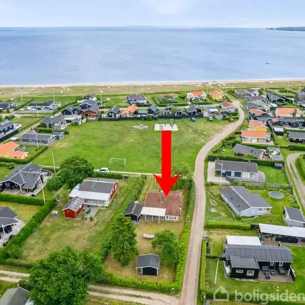 Hus vist ovenfra med rød pil pegende på det. Det ligger i et kvarter tæt ved stranden. Omkringliggende huse og veje i kystområde.