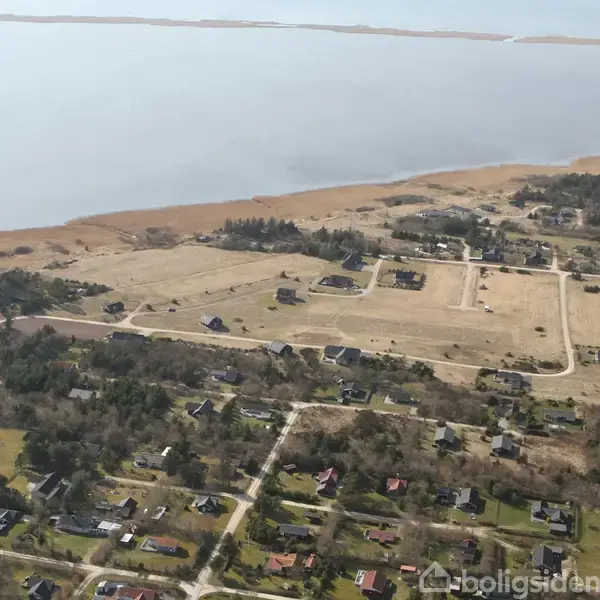 Landsbyområder med huse spredt over et landligt landskab, der grænser op til en stor vandflade. Området er præget af åbne grønne arealer og skovområder.