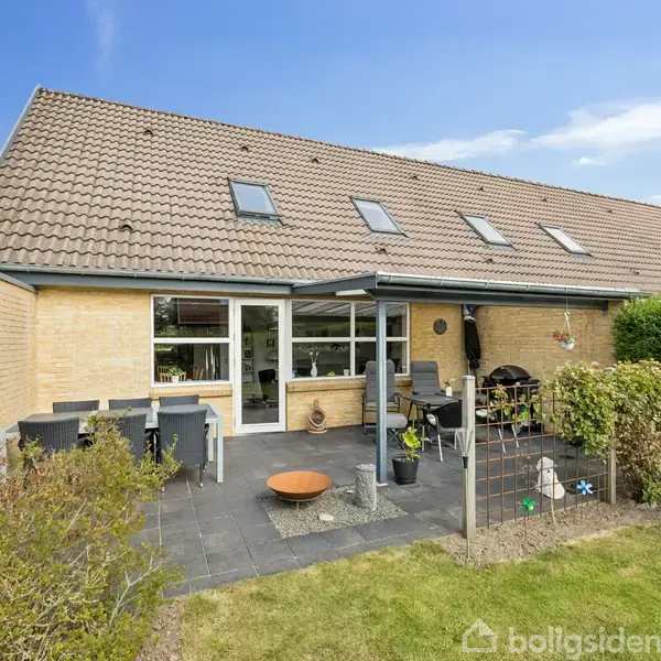 Garderobeområde med sorte jakker hænger på knager ved siden af et gråt skoskab. Entré med en kommode, ovalt spejl, keramisk vase og en dekoration formet som en kat.