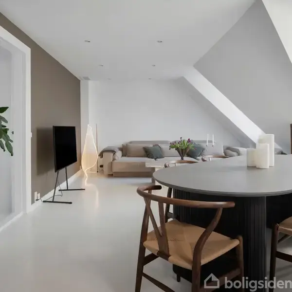 Et spisebord med stole står i et moderne, lyst stueområde. Der er en sofa med puder i baggrunden og en stor plante i en krukke. En fladskærm står på gulvet.
