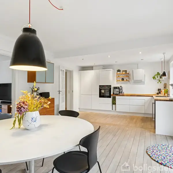 Rækkehus med rødtag normalt gavl, sort bil parkeret foran, omgivet af skraldespande og træer i indkørsel. Adresse på dør: "19".