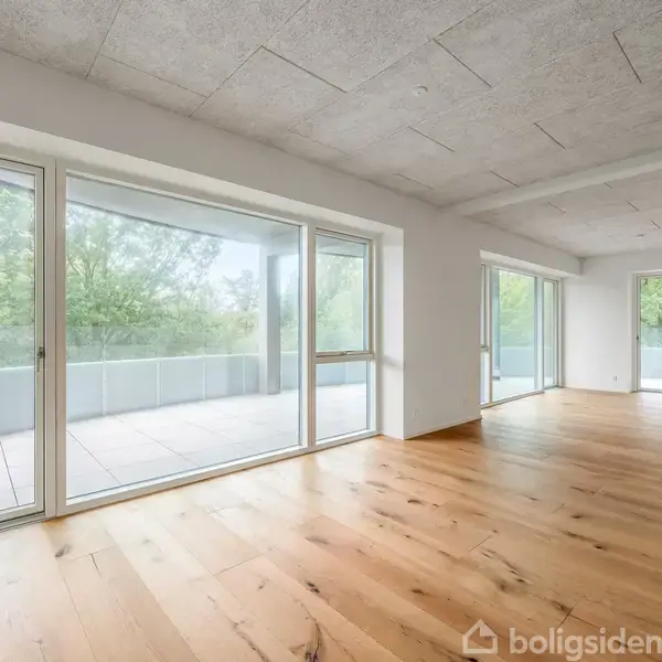 Lyse, tomme rum med trægulve. Store vinduer med udsigt til en balkon og grønne omgivelser. Minimalistisk og rummeligt design i en moderne bygning.