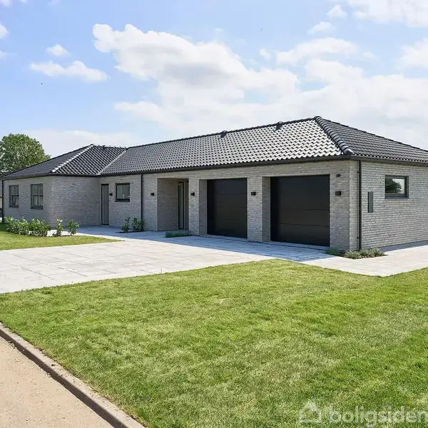 En moderne enfamiliehus med gråt murstensfacade står på en nyanlagt græsplæne. Huset har to indbyggede garager og en flisebelagt indkørsel, placeret i et villakvarter med blå himmel.