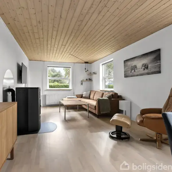 Stue med brun sofa og lænestol, trægulv, og træloft. Væggene har vinduer, hylder og billeder. Rummet er lyst med et moderne skandinavisk design og minimalistisk indretning.