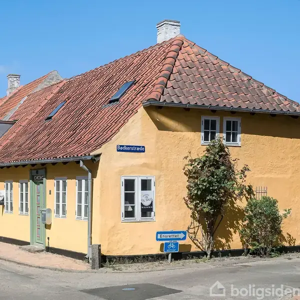Gulmalet hus med rødt tegltag står på hjørnet af Bøderstræde og en anden vej. Gadeskilte viser navnene "Bøderstræde" og "Legeareal". Omkringliggende huse med lignende stil ses i byen.