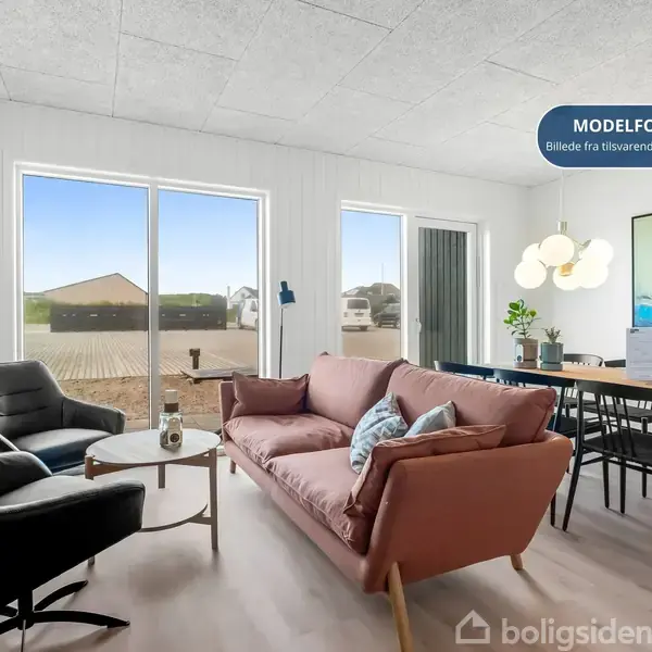 Stue med en lyserød sofa og sorte lænestole står foran store vinduer. Ved siden af er et spisebord med seks stole. Over bordet hænger en moderne lampe. Tekst: "MODEL FOTO Billede fra tilsvarende lejlighed".