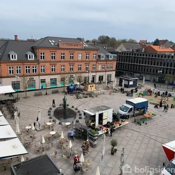Torv med opstillet marked, mennesker går omkring og nogle sidder ved caféborde. Baggrund domineres af en rød murstensbygning med teksten "Sparekassen Bredebro". Vejret virker klart og koldt.