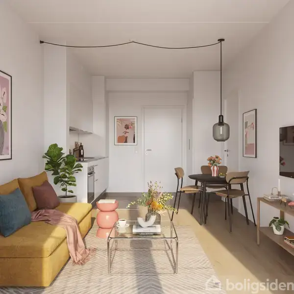 En stue med en sennepsfarvet sofa fyldt med puder, vendt mod et fjernsyn på en reol. Ved siden af, et glasbord med blomster, en spisestue med fire stole og kunst på væggene.